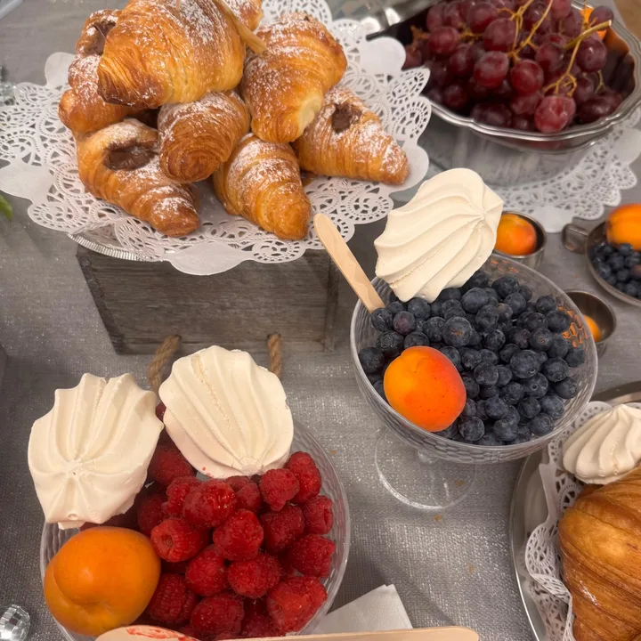 Breakfast table with croissants, meringues and berries